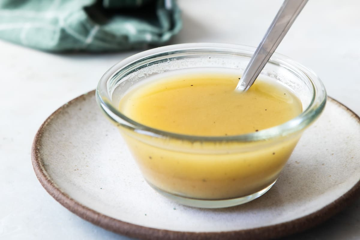 Apple cider vinaigrette in a clear bowl with a spoon.