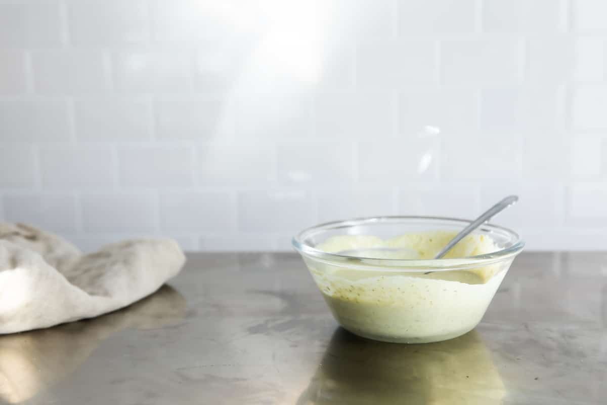 Dressing for a caprese sandwich in a small clear bowl.