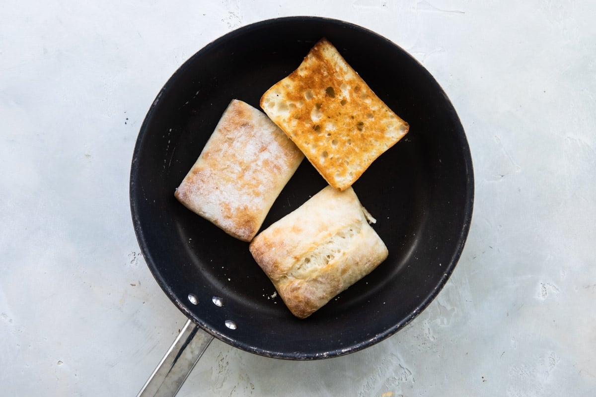 Caprese sandwich bread being toasted in a skillet.