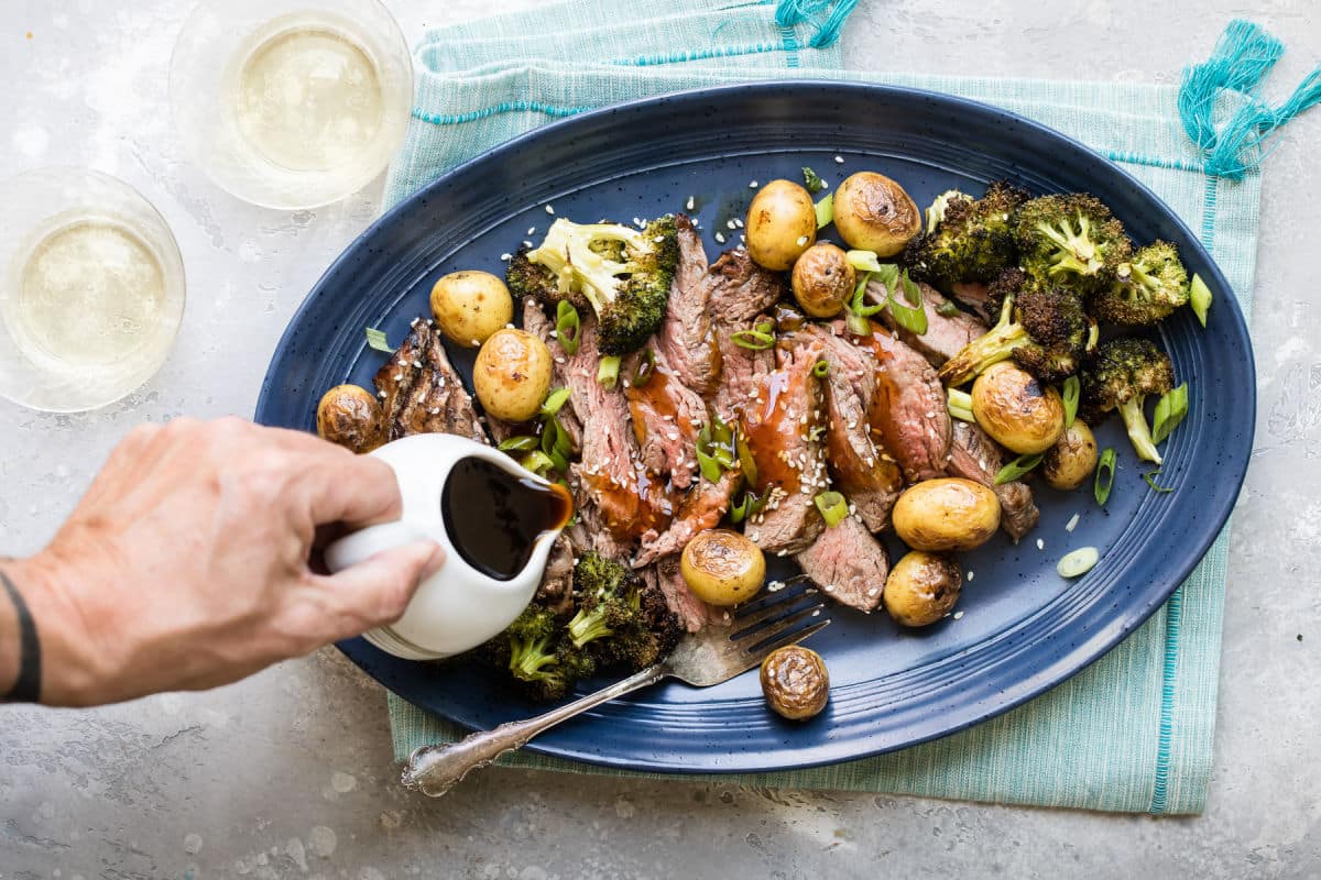 A platter of Hibachi Steak with Grilled Wasabi potatoes and teriyaki sauce being drizzled over it.
