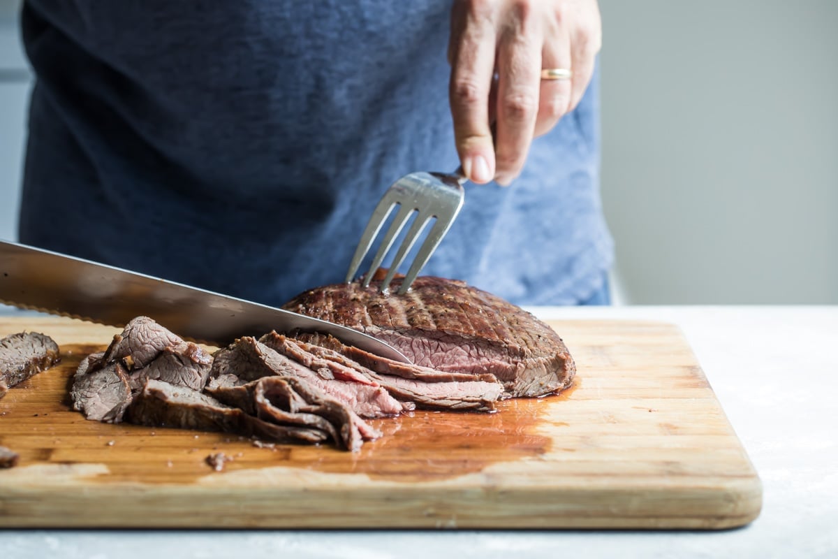 Slicing Hibachi steak on a wooden cutting board.
