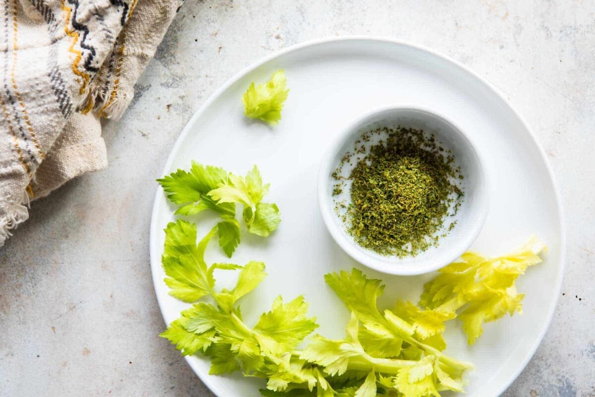 Celery salt in a small white bowl that is resting on a white plate.