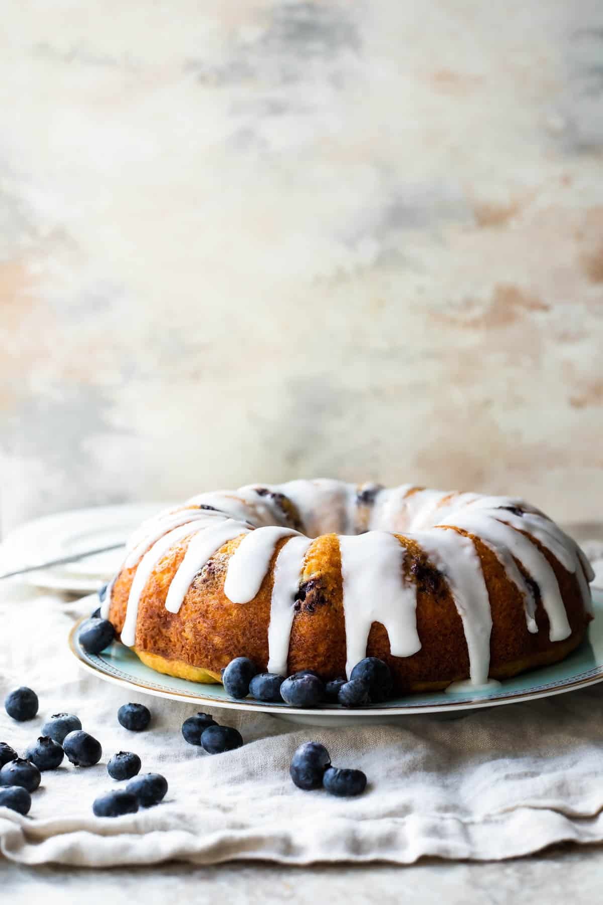 A Lemon Blueberry Cake with glaze on a platter.