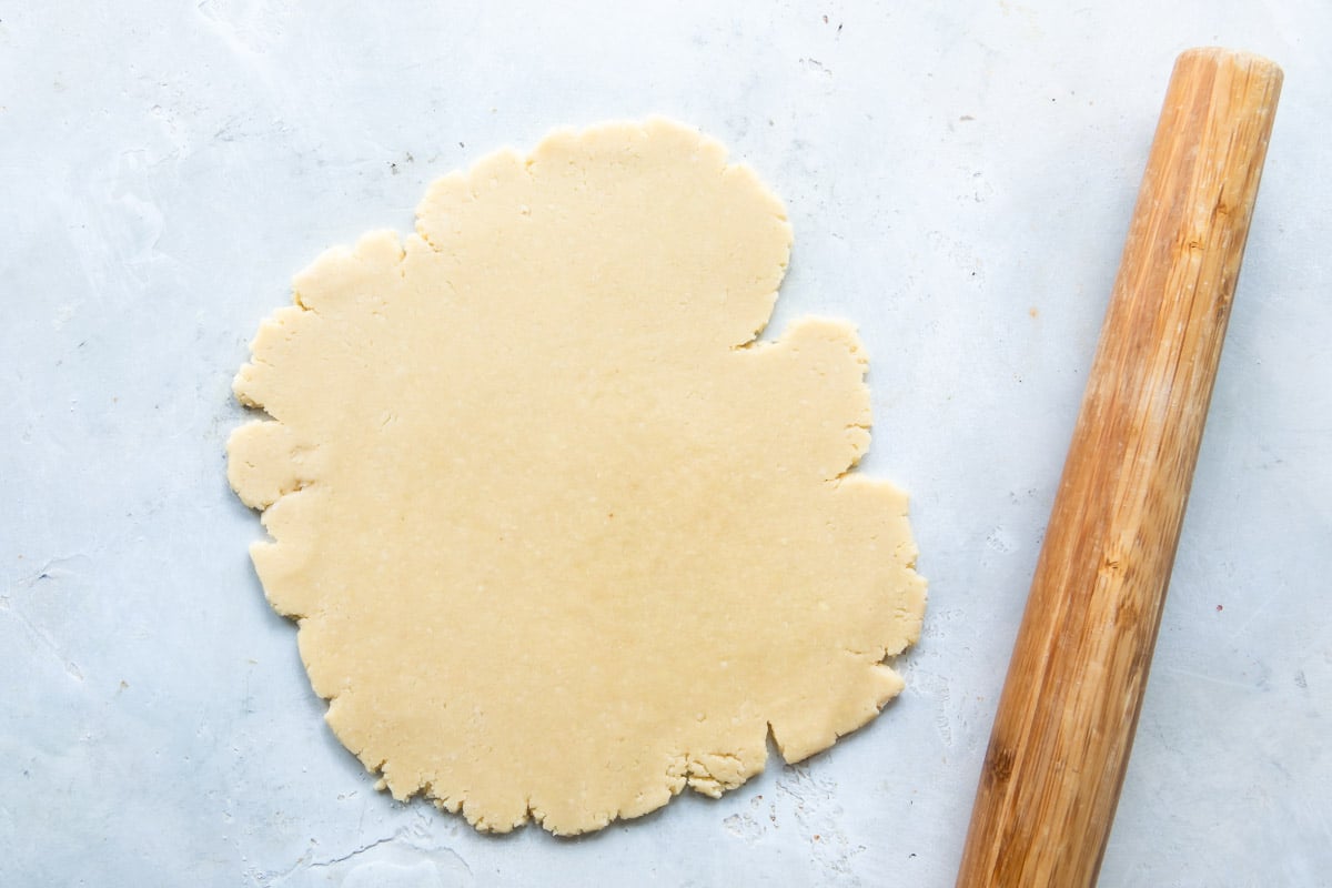 Linzer cookie dough rolled out next to a rolling pin.