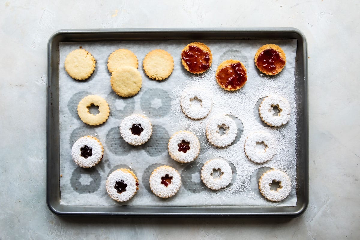 Linzer cookies being assembled on a baking sheet.