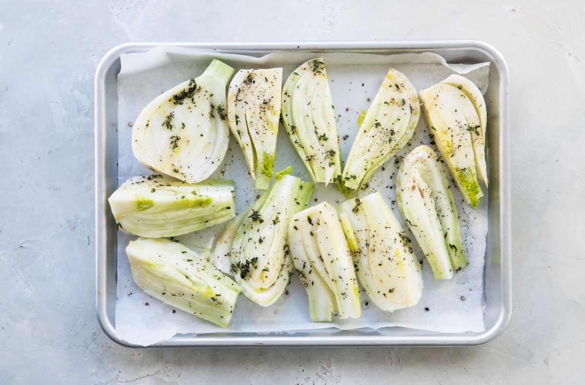 Uncooked fennel on a parchment paper lined baking sheet.