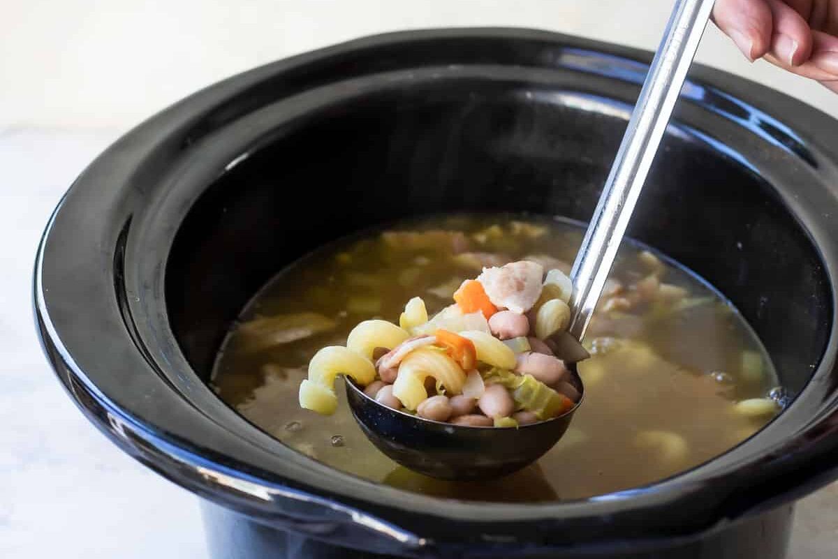 Someone scooping a ladle of soup out of a slow cooker.