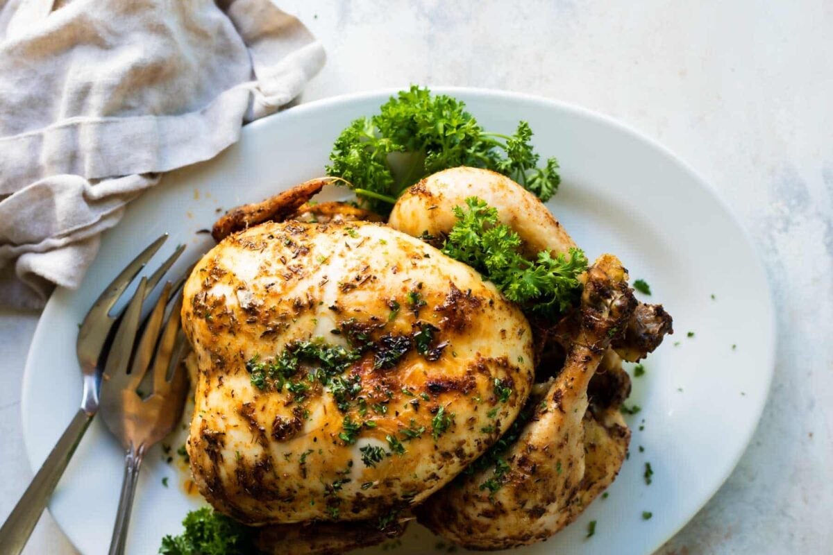 A rotisserie chicken on an oval serving plate.