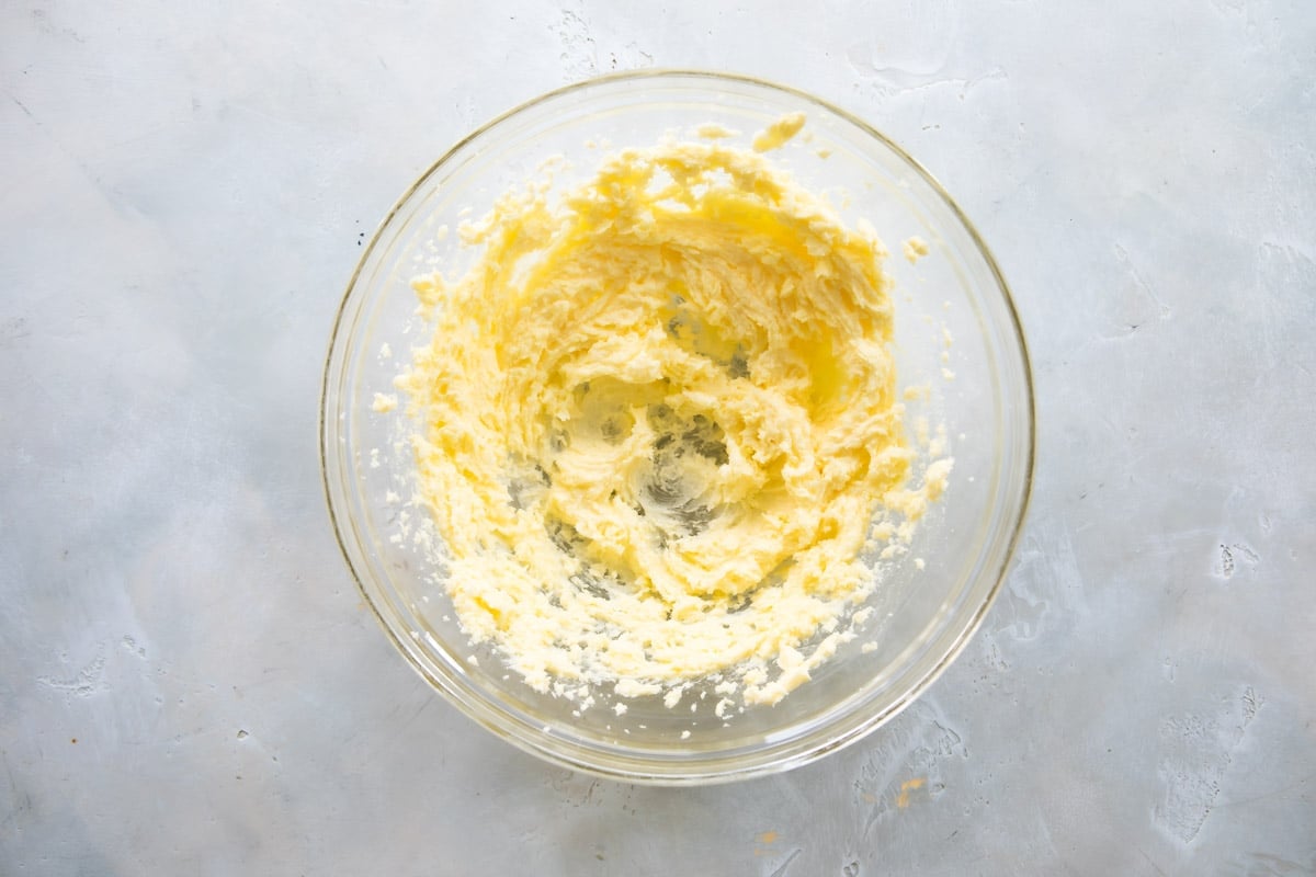 Wet ingredients for spritz cookies after being mixed in a clear glass bowl.