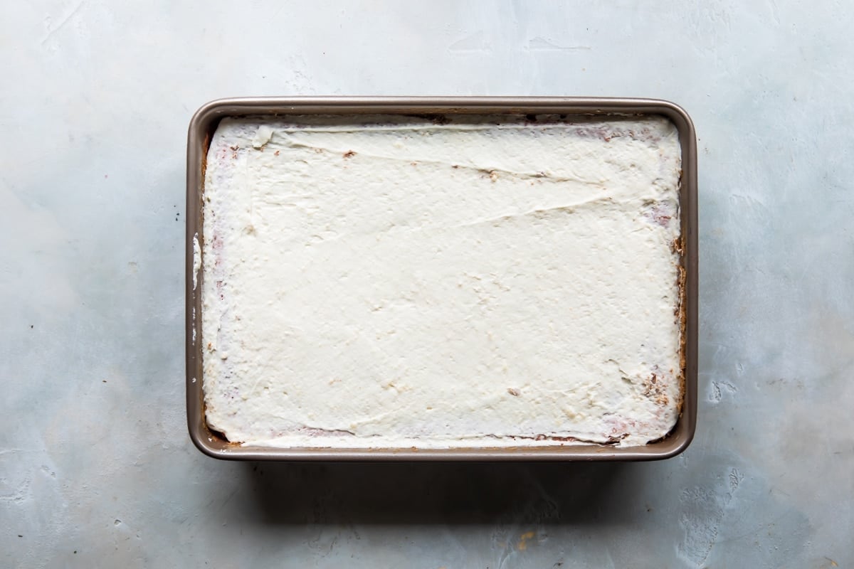 A strawberry jello poke cake before being topped with berries.