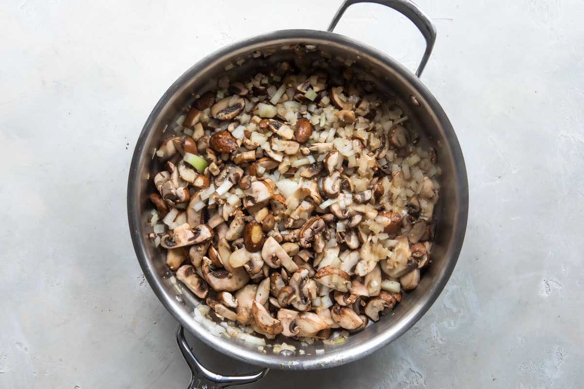 Vegetables being cooked in a silver skillet for vegetable pot pie.