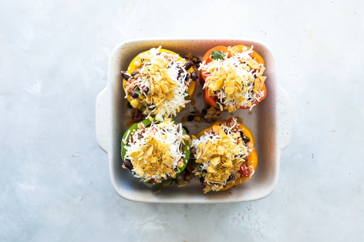 Vegetarian stuffed peppers in a white baking dish before being baked.