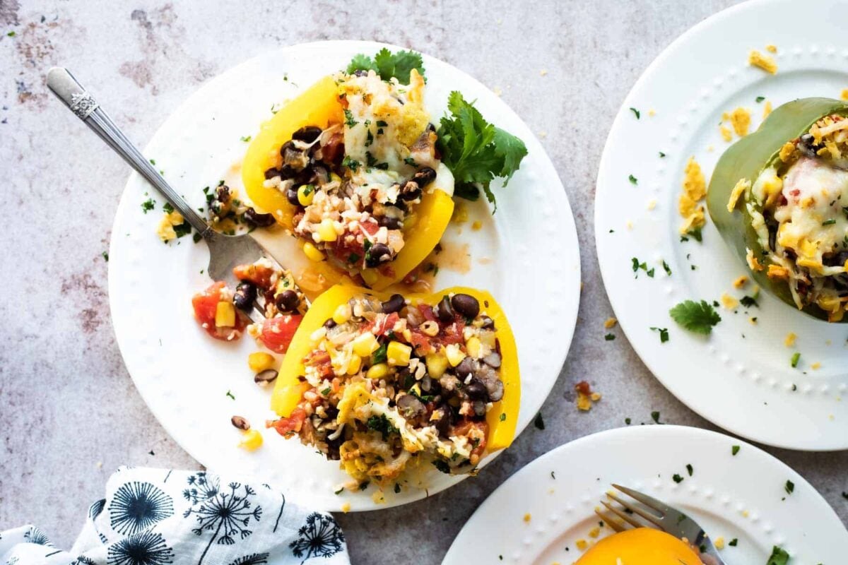 Two vegetarian stuffed peppers and a fork on a white plate.