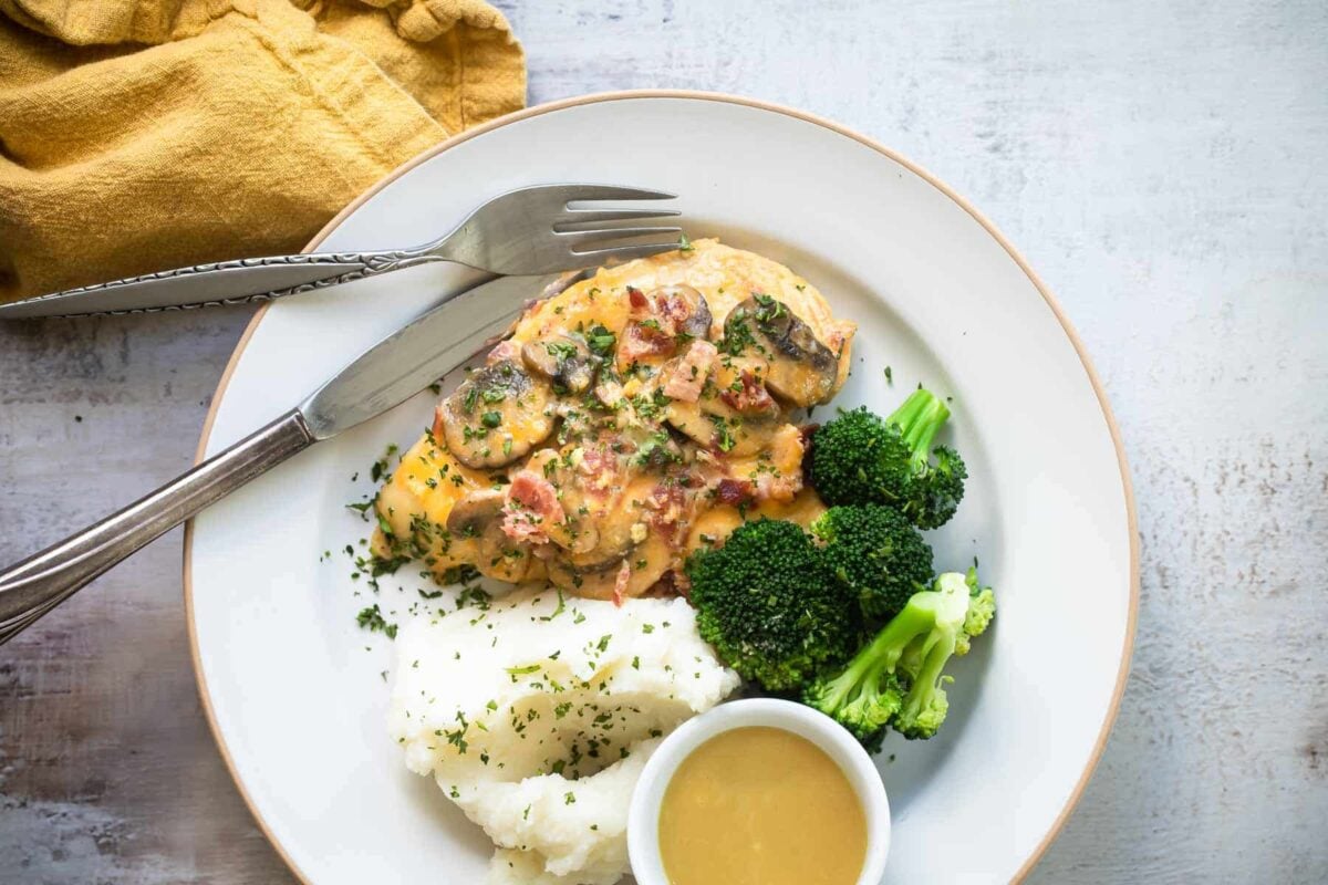 Alice Springs chicken on a white plate with sides of broccoli and mashed potatoes.