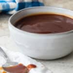 Barbecue sauce in a small gray bowl with a spoon next to it.