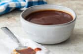 Barbecue sauce in a small gray bowl with a spoon next to it.