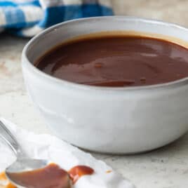 Barbecue sauce in a small gray bowl with a spoon next to it.