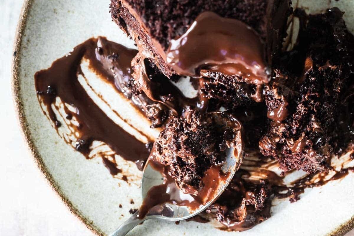 A piece of chocolate cake with chocolate sauce on top.