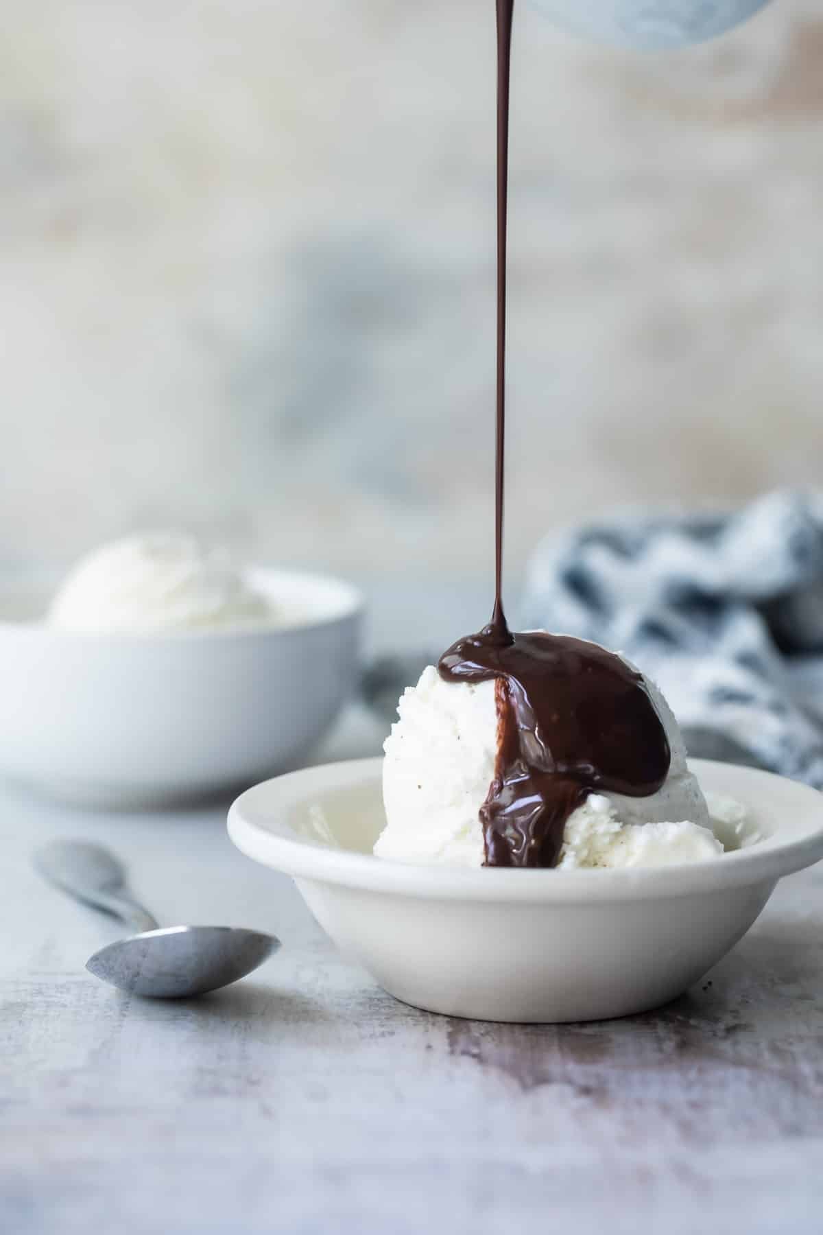 Chocolate syrup being drizzled onto vanilla ice cream.