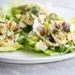 A white plate with lettuce cups filled with curried chicken salad.