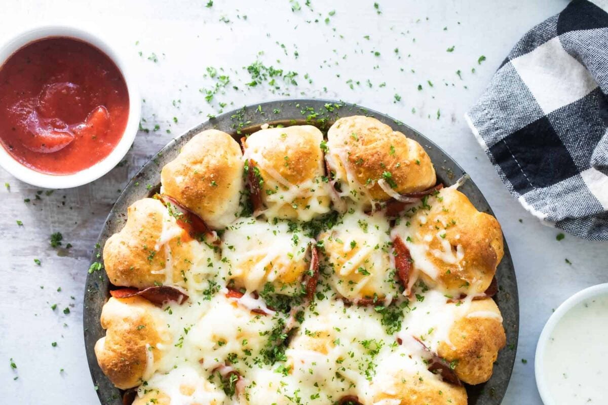 Pepperoni pizza bites next to a bowl of marinara sauce.