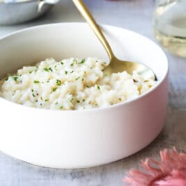 Risotto in a white bowl with a gold spoon.