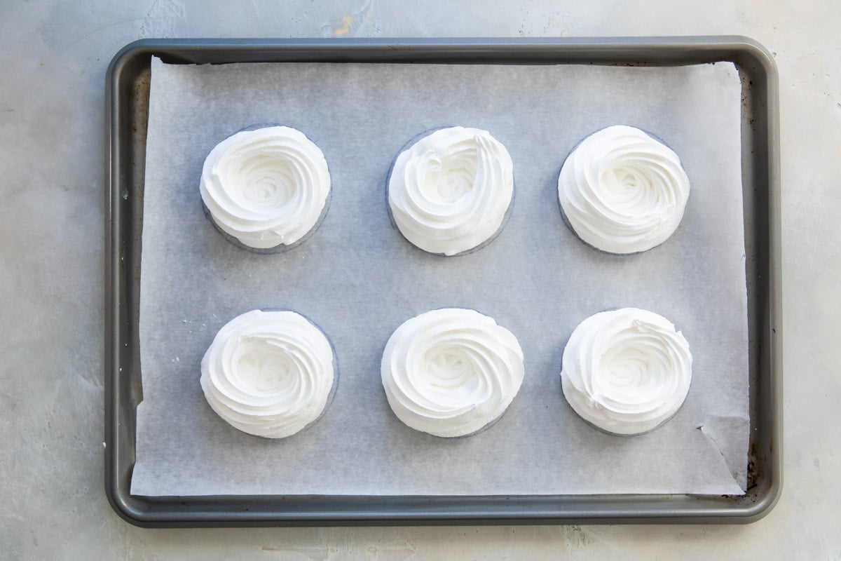 Schaum tortes on a parchment paper lined baking sheet.