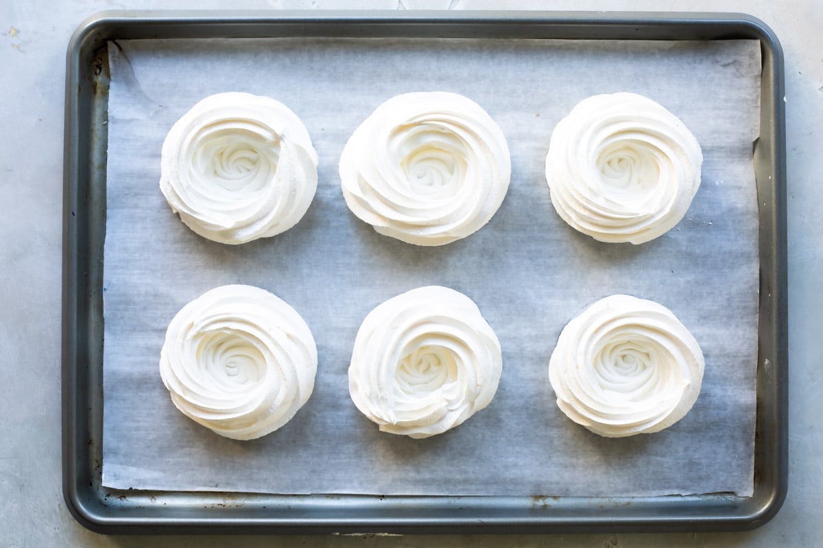 Schaum tortes on a parchment paper lined baking sheet.