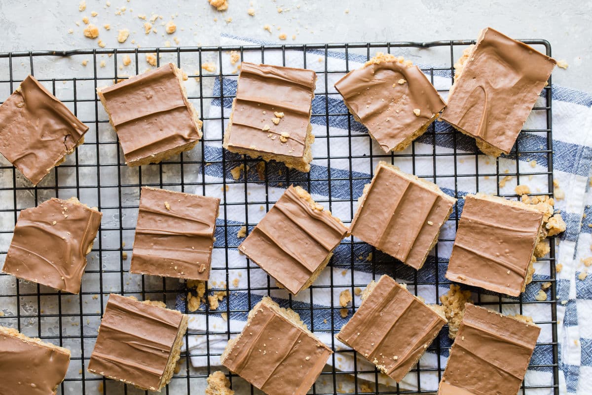 A cooling rack with lots of Scotcheroos arranged in a single layer on it.