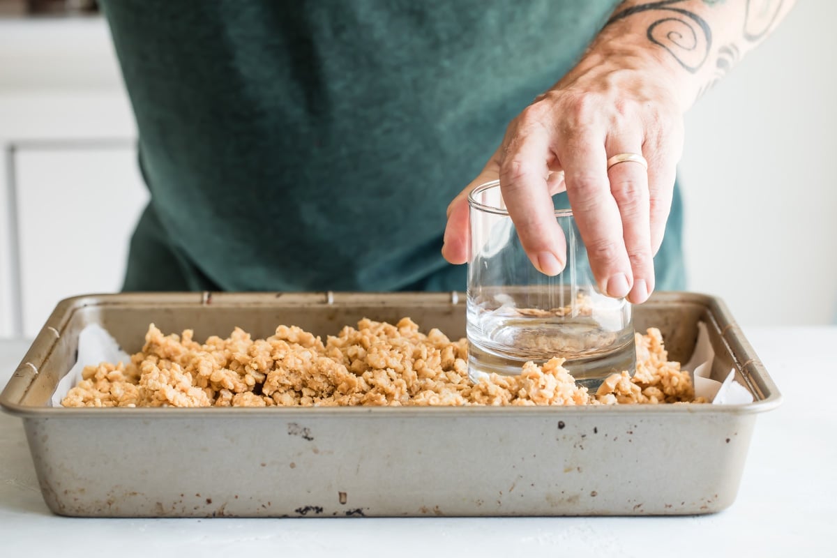 Using a jar to press Scotcheroos into a baking pan.