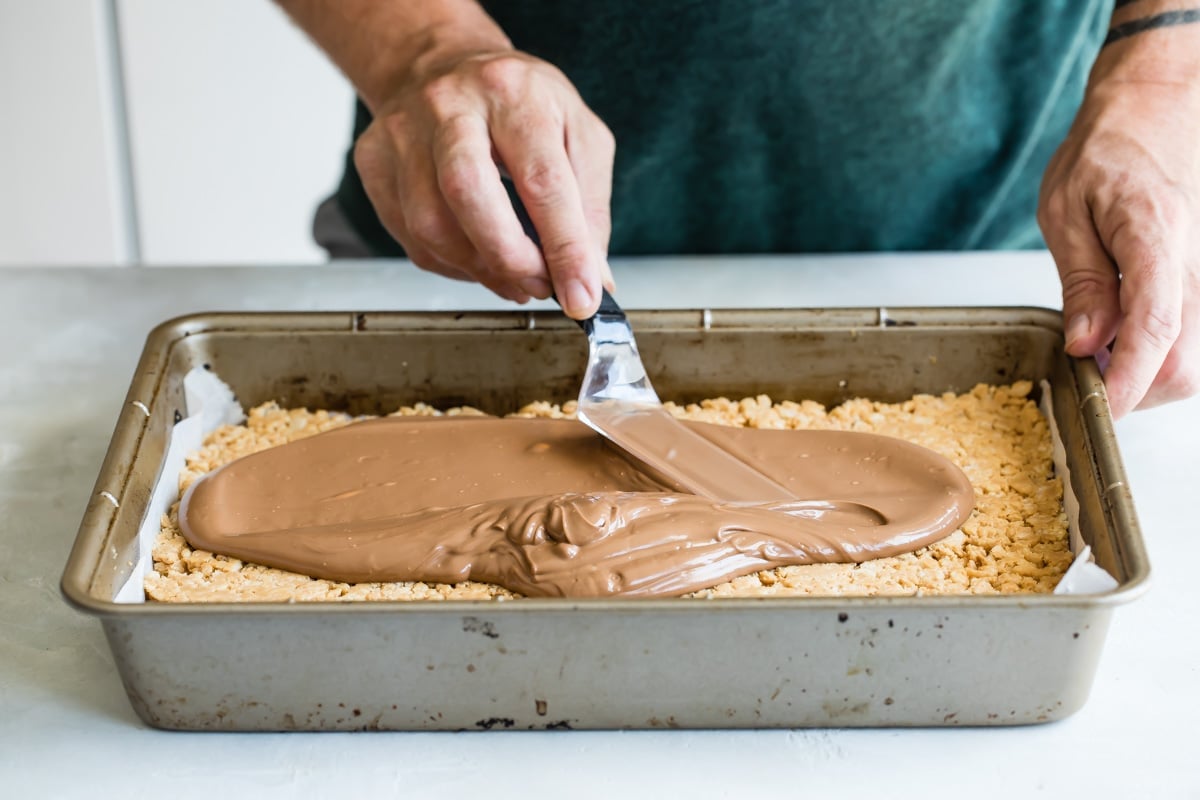 Spreading frosting over Scotcheroos.