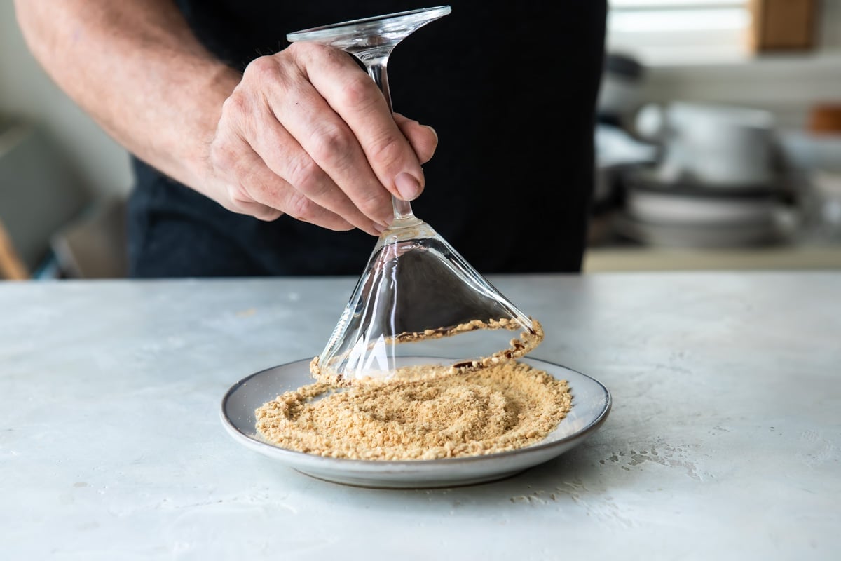Rimming a cocktail shaker with graham cracker crumbs.