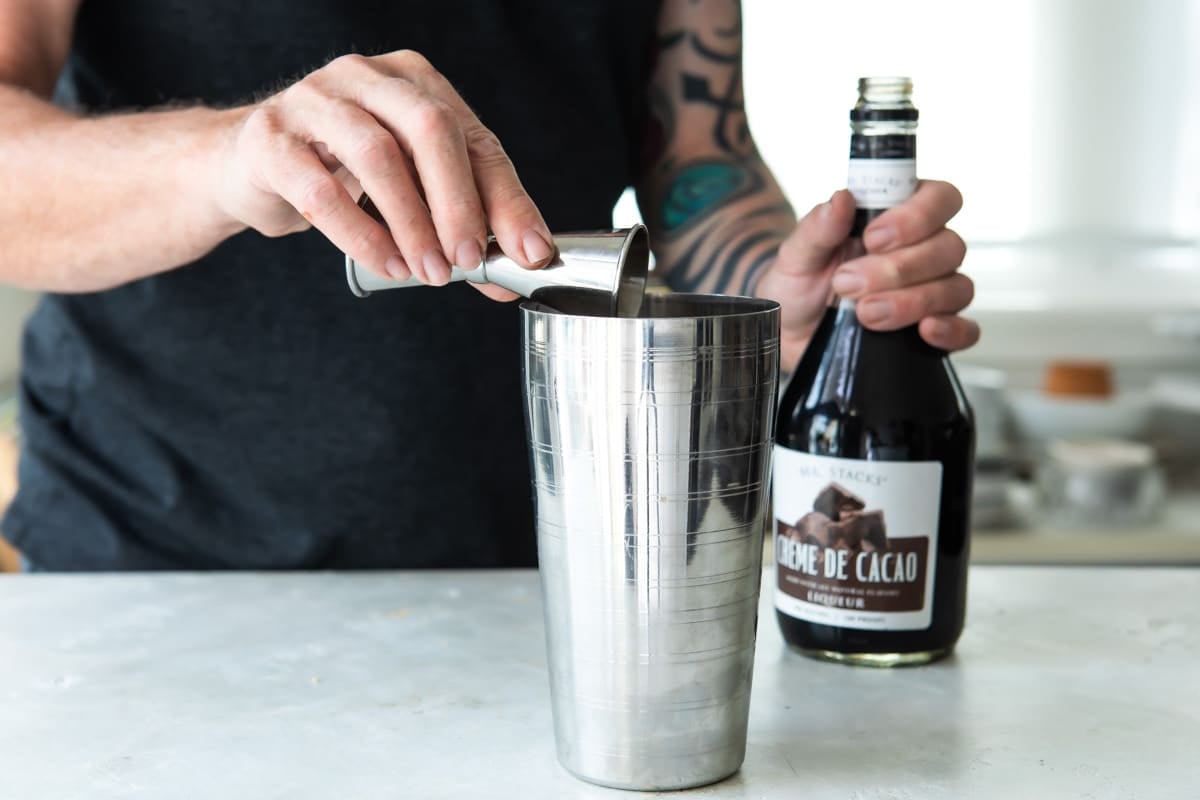 Adding liquor to a cocktail shaker.