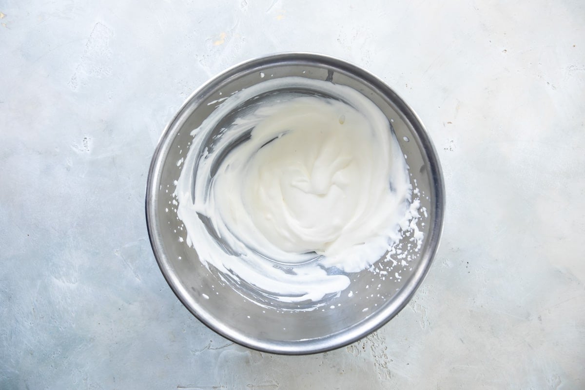 Dressing for waldorf salad in a silver mixing bowl.