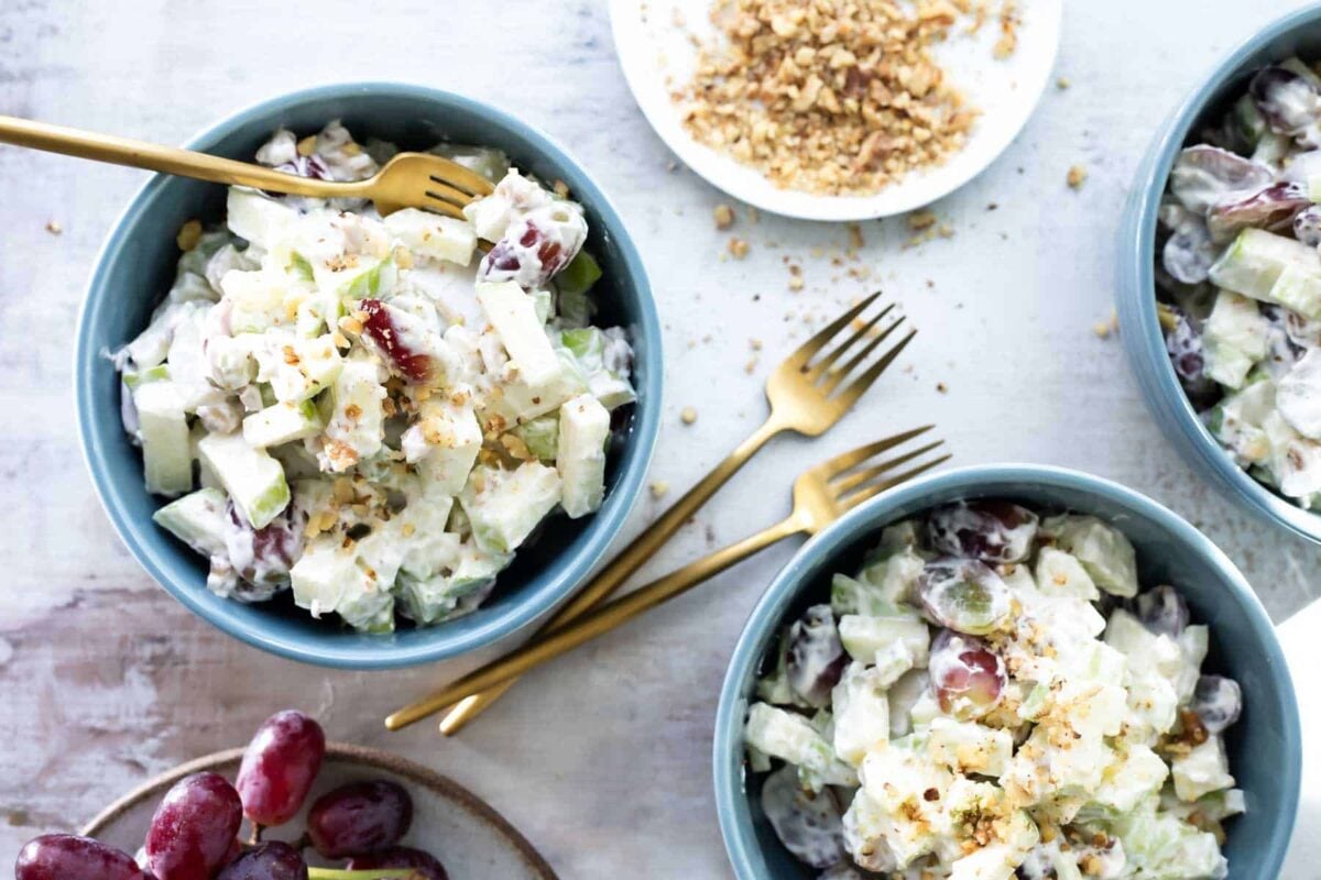 Three blue bowls with waldorf salad in them.