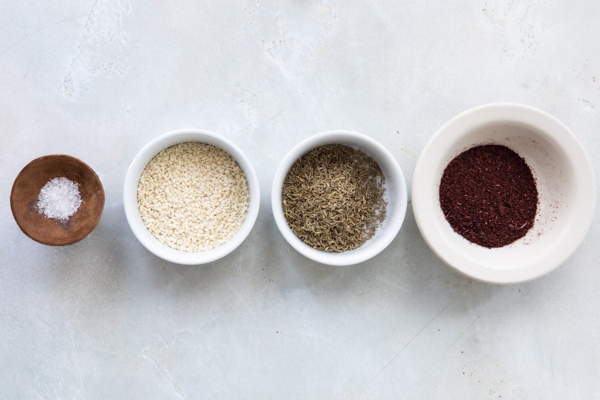 Four small bowls with ingredients for za'atar seasoning.