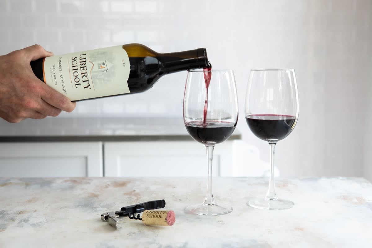 Someone pouring a glass of red wine.