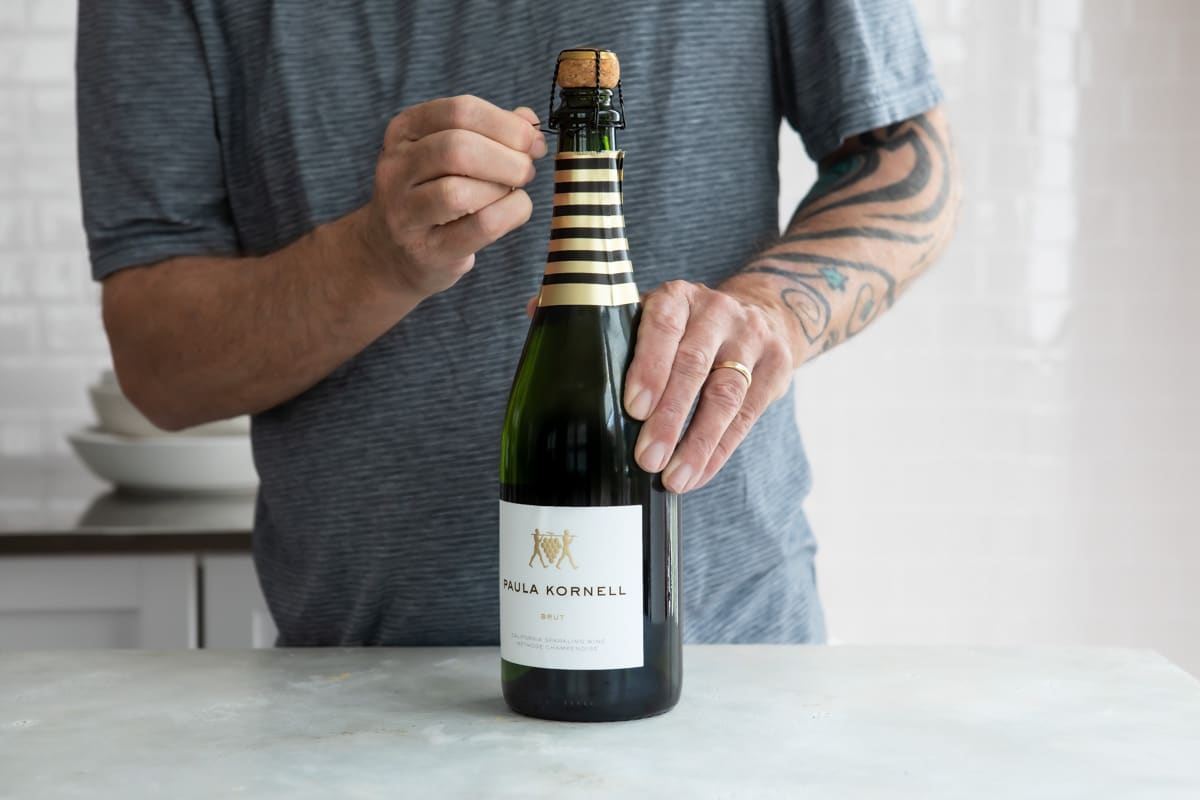 Removing the cork cage from a bottle of champagne.