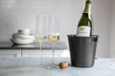 A bottle of champagne chilling near 2 full glasses.