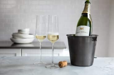 A bottle of champagne chilling near 2 full glasses.