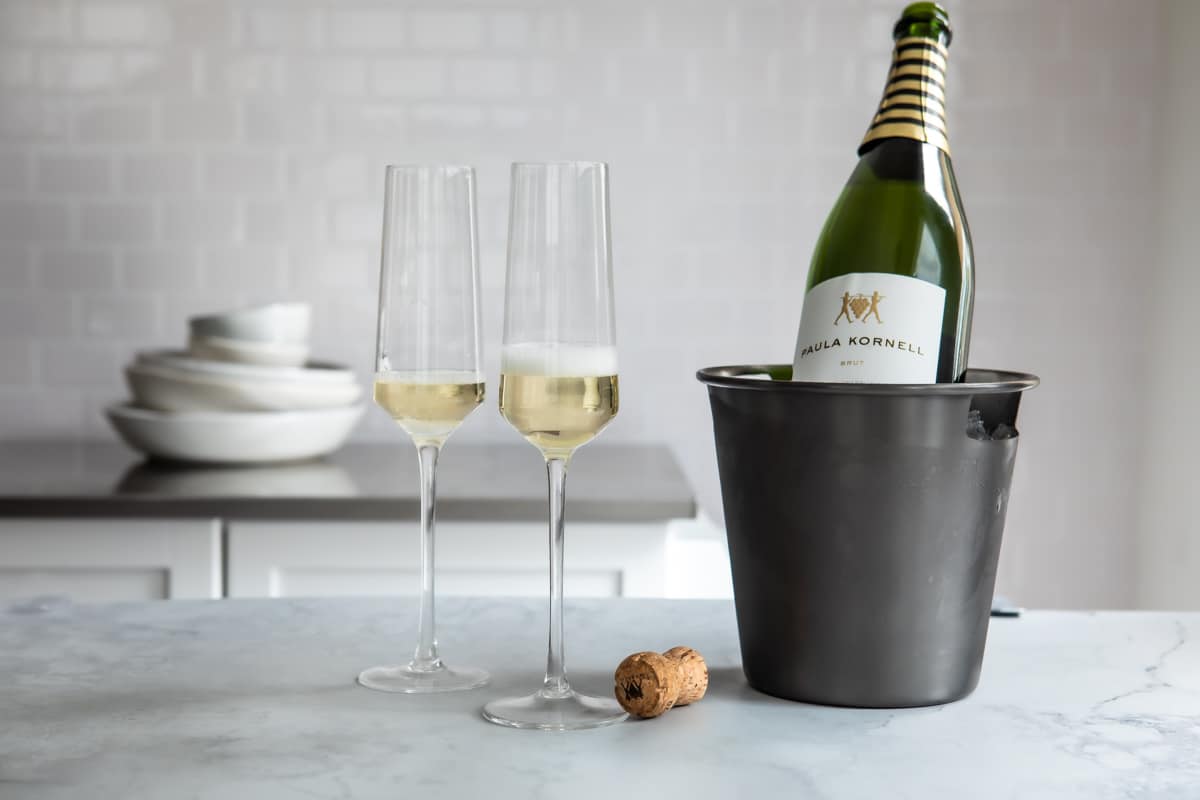 A bottle of champagne chilling near 2 full glasses.