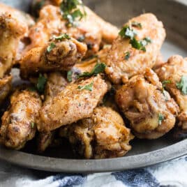A bowl of Chinese chicken wings next to some pints of beer.