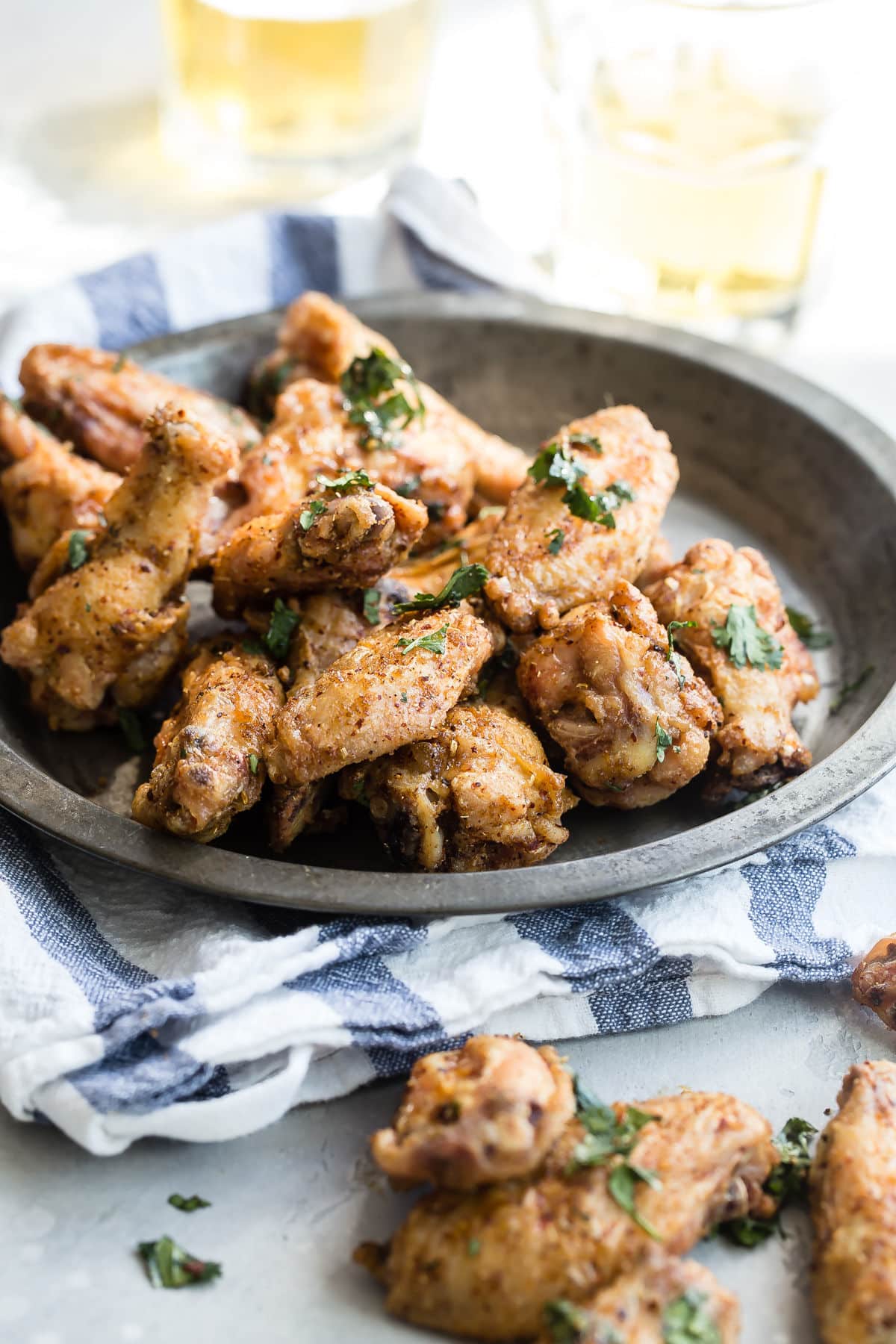 A bowl of Chinese chicken wings next to some pints of beer.
