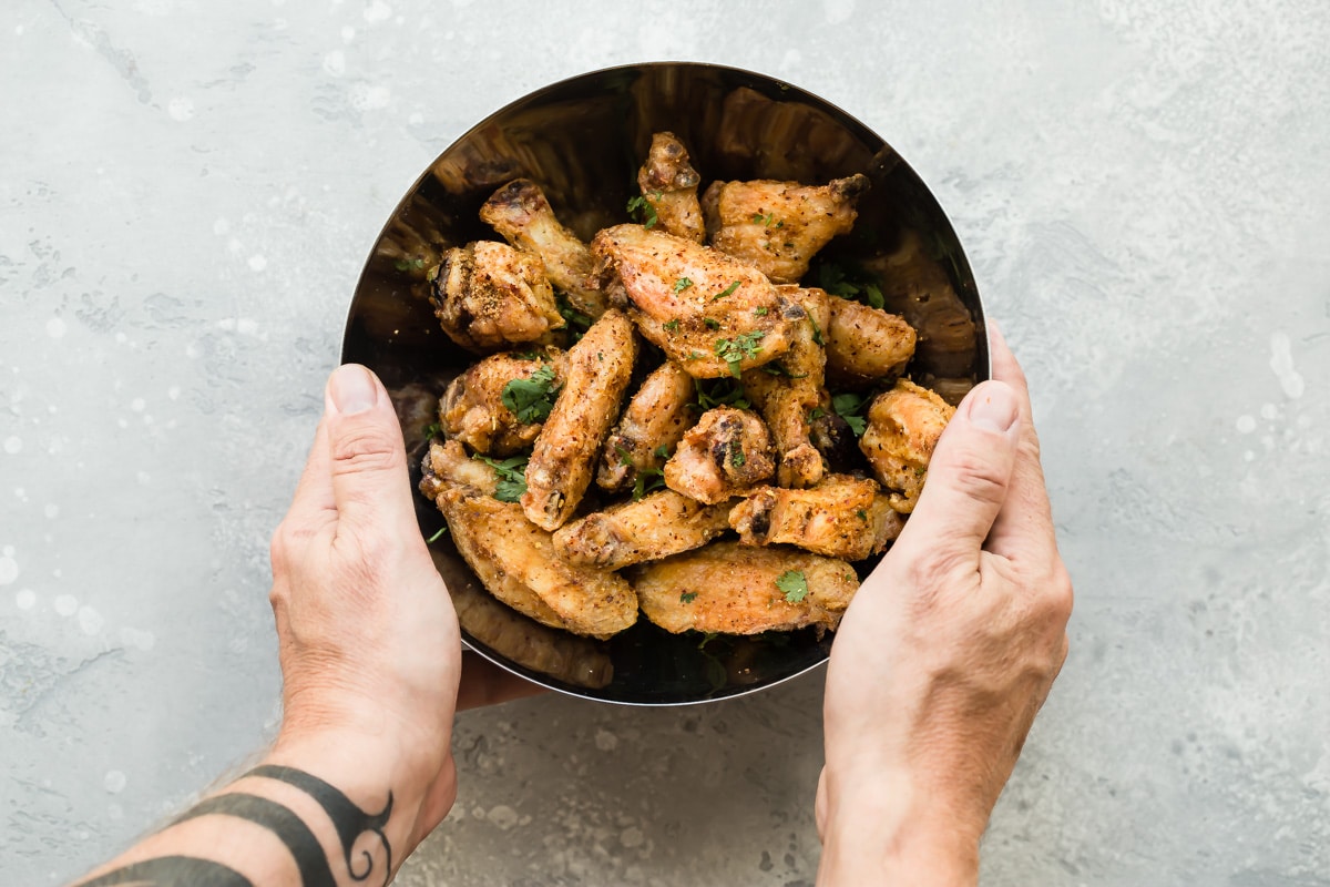 Someone tossing chicken wings with a Chinese spice blend.