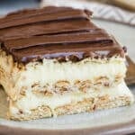 Slices of no-bake Chocolate Eclair Cake on white plates with forks.