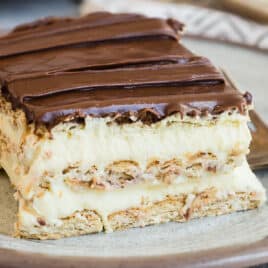 Slices of no-bake Chocolate Eclair Cake on white plates with forks.