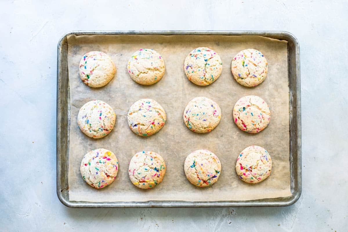 Twelve Confetti cookies on a baking sheet after being baked.