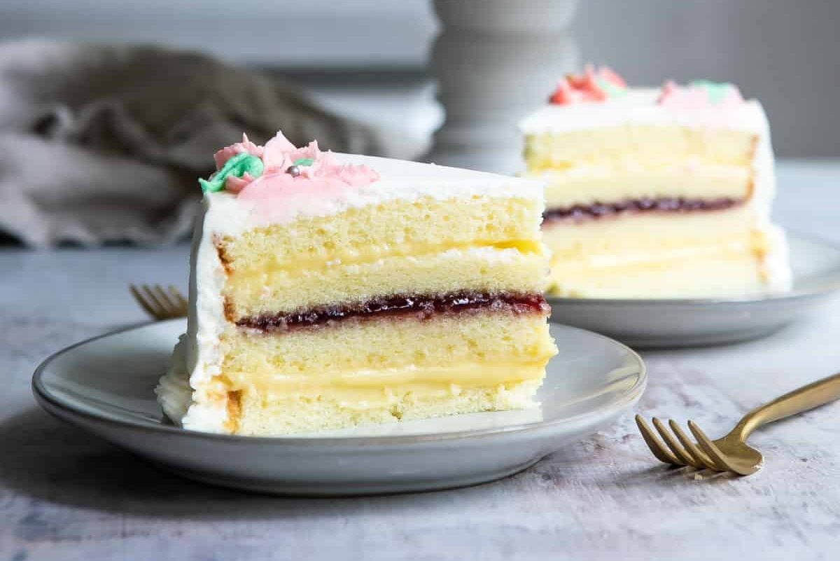 A cut Danish Layer Cake with slices on plates nearby.