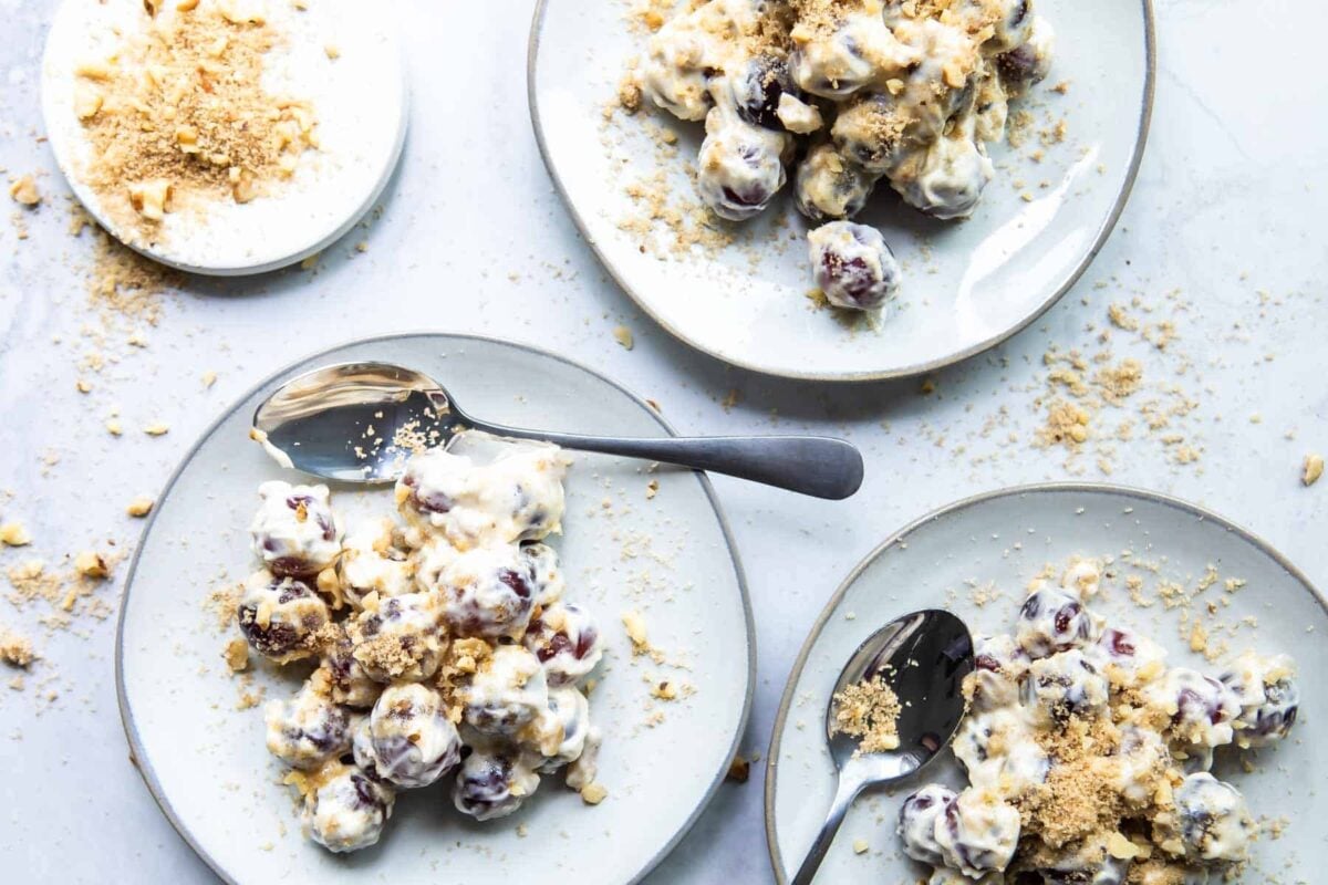 Small plates of grape salad with spoons.