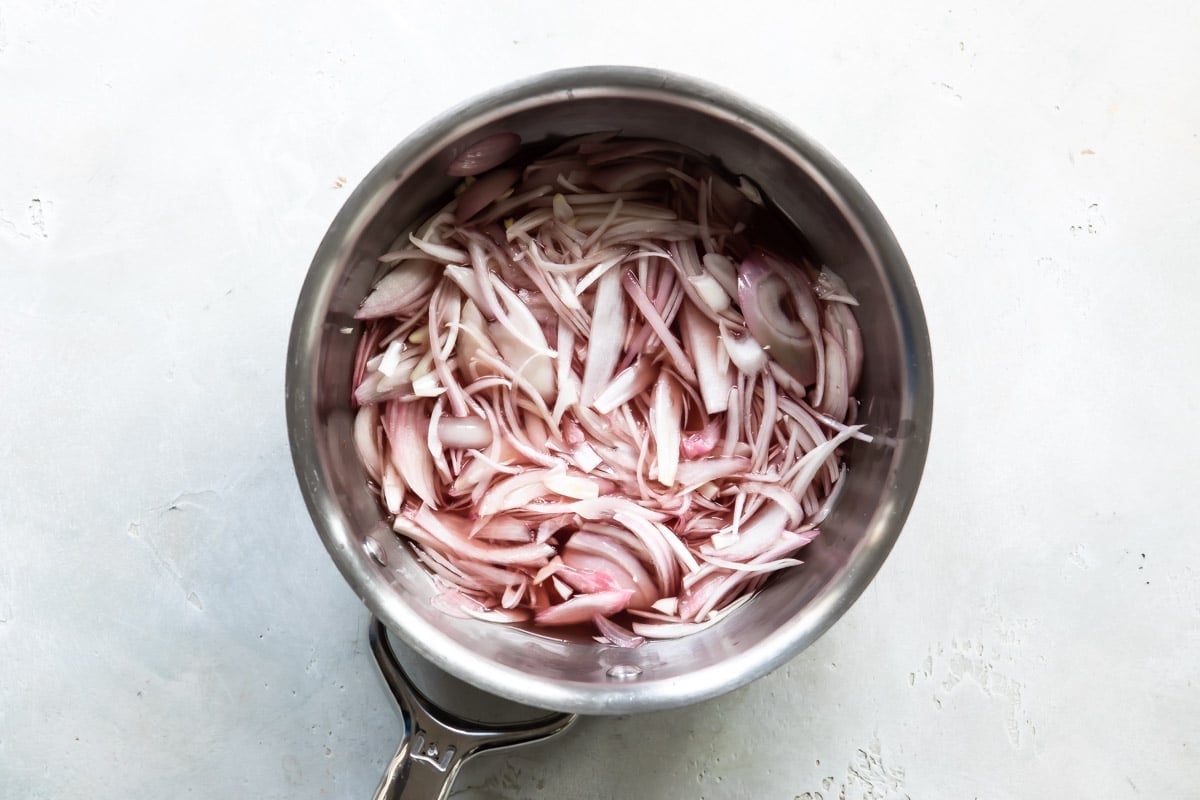 A saucepan full of sliced shallots before pickling.
